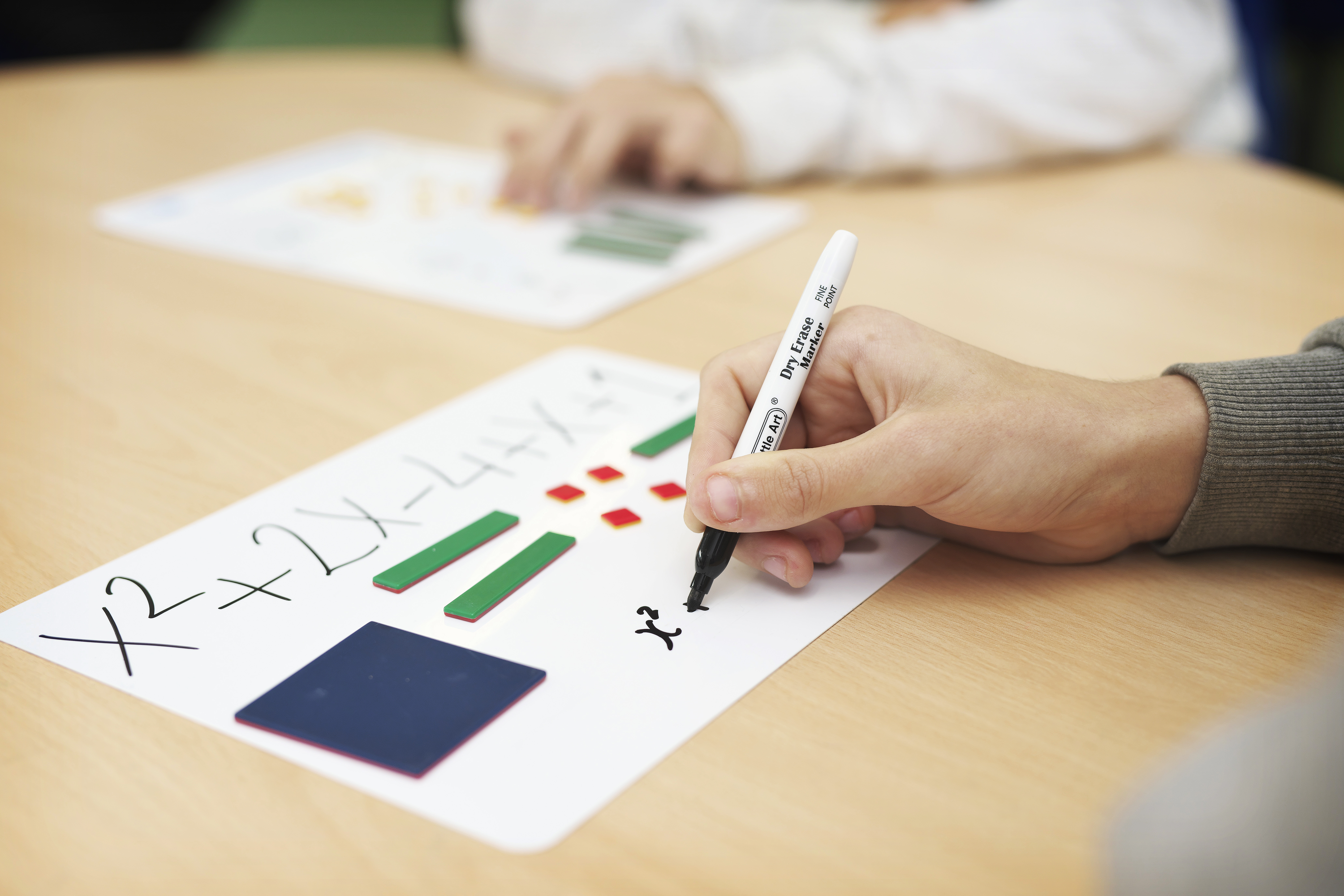 Person writing a mathematical equation on a mini whiteboard