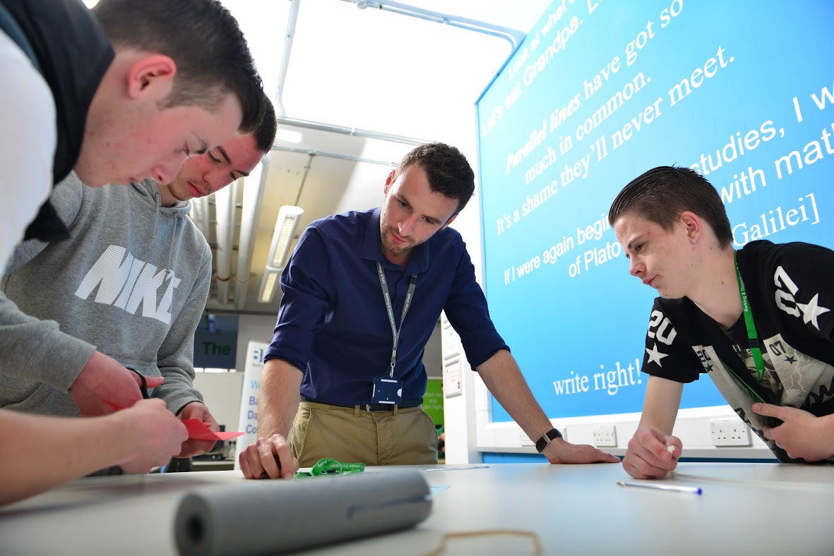 Three Students And Teacher Working Together On A Task