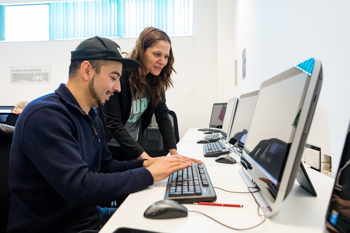 Teacher Helping A Student In A Digital Class