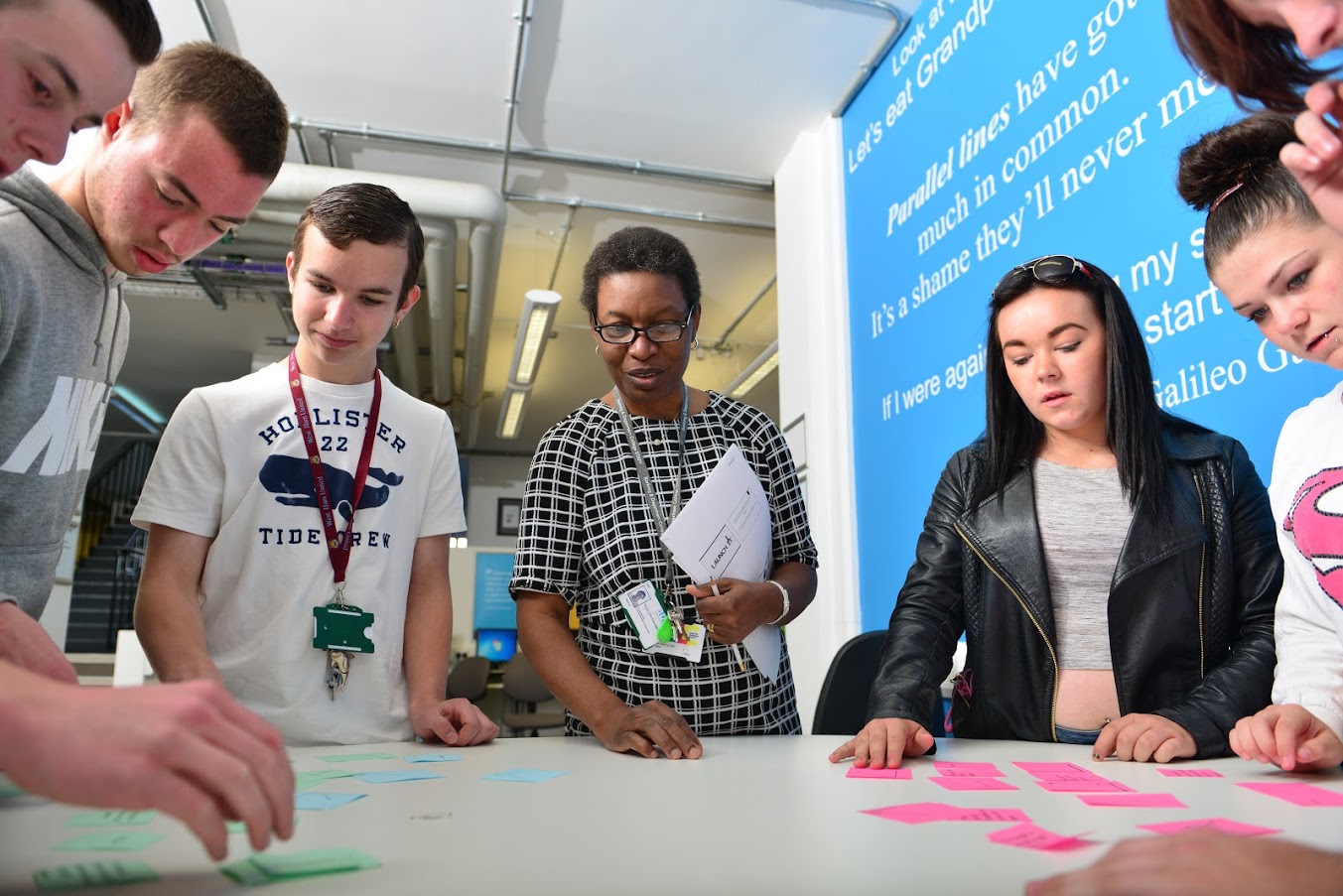 Teacher and students grouped around a desk working on a project